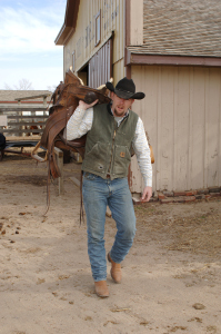 Rancher carrying a saddle
